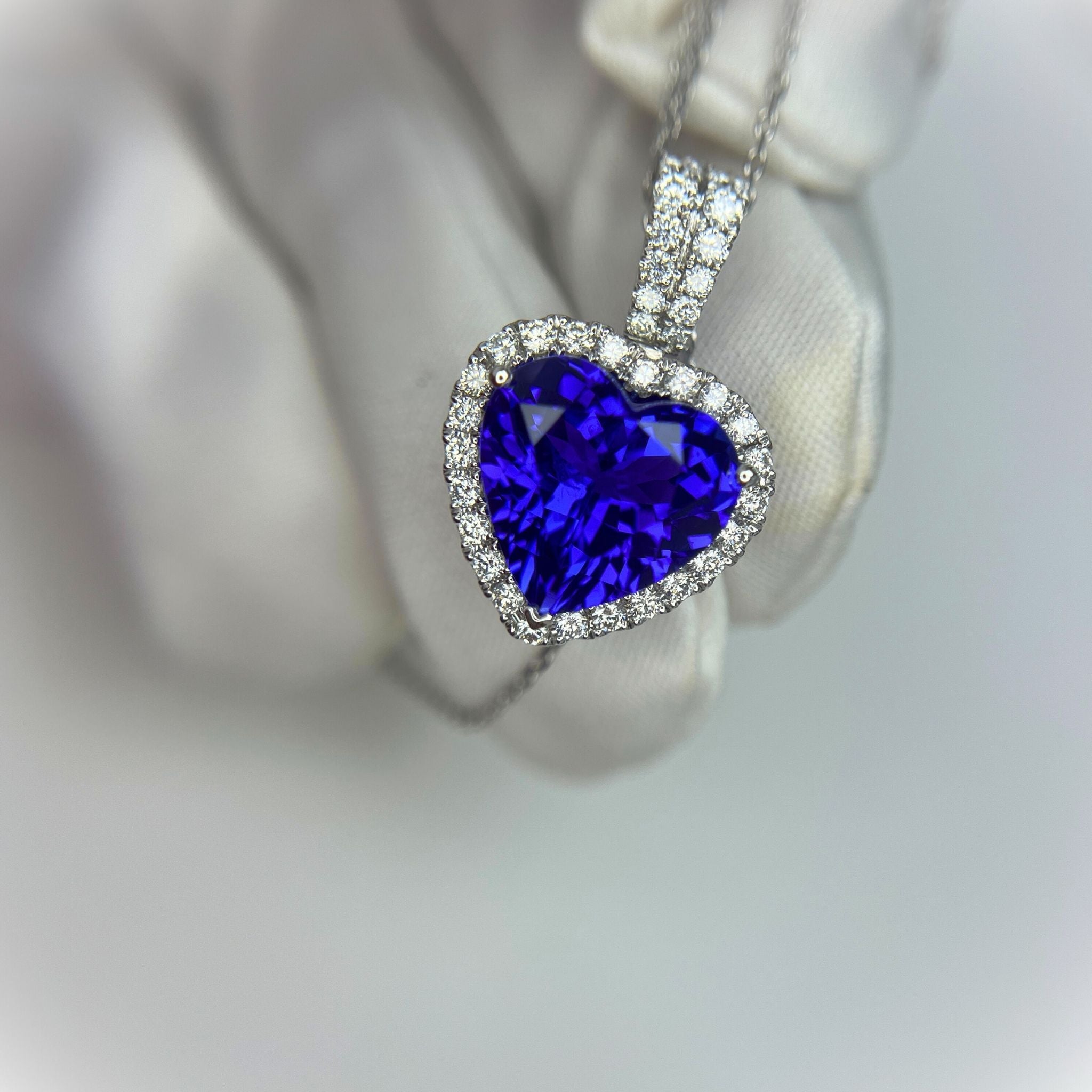 Heart-shaped tanzanite blue gemstone pendant with diamond accents on a white background