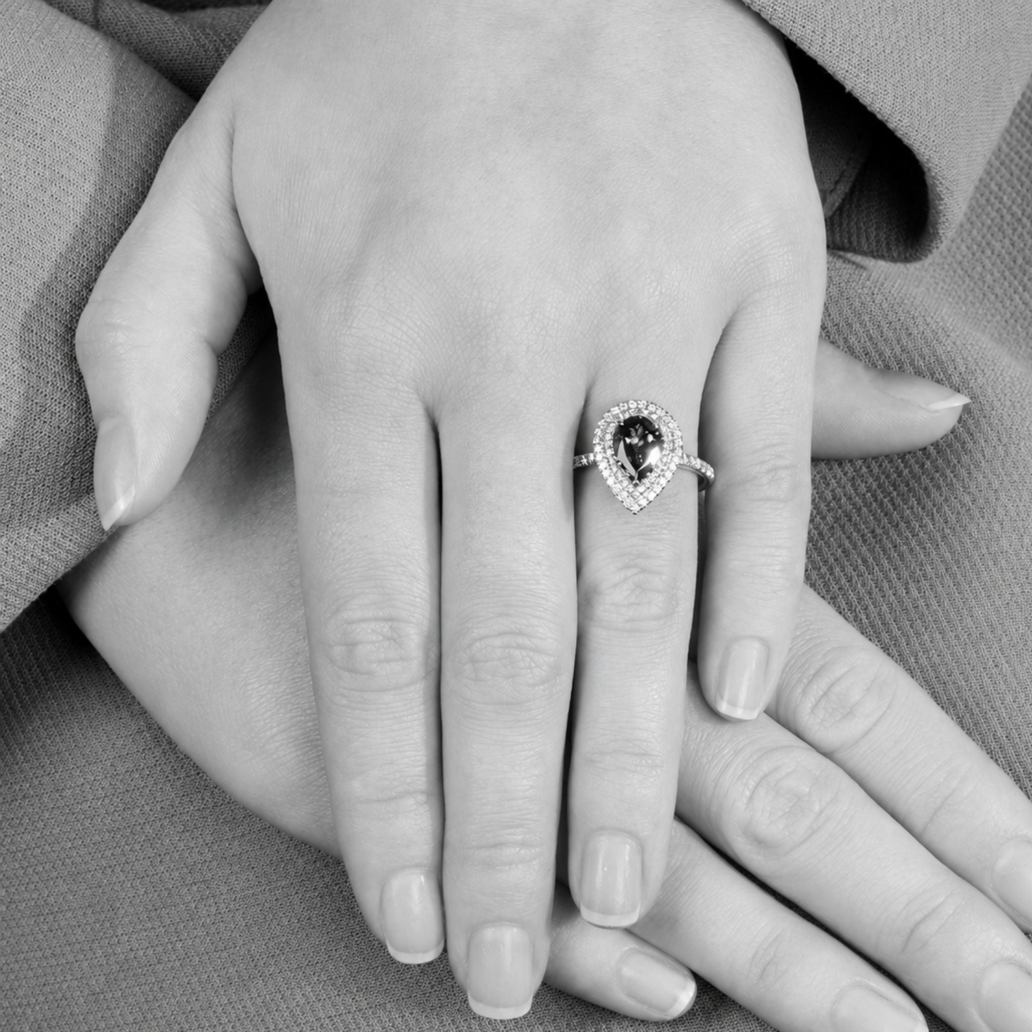 A close-up of a hand wearing a pear shaped shaped ring 